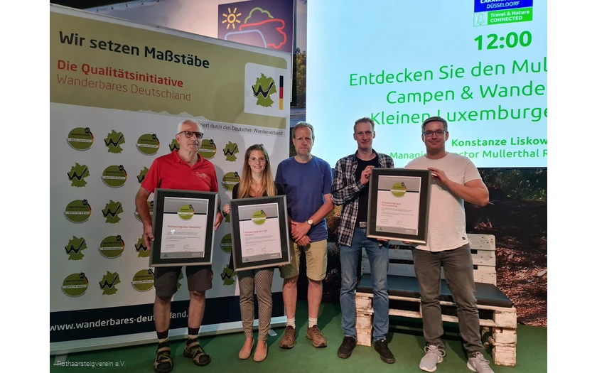Gruppe auf einer Bühne mit Urkunden der zertifizierten Wege