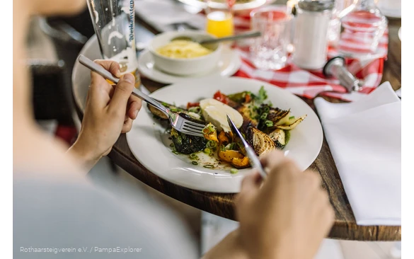Nahaufnahme von einem Teller mit Antipasti und Händen die Besteck halten