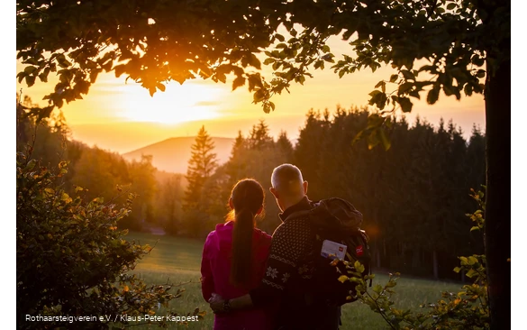 Zwei Rothaarsteig-Wanderer schauen in den Sonnenuntergang auf der Rothaarsteig-spur Sorper Panoramapfad
