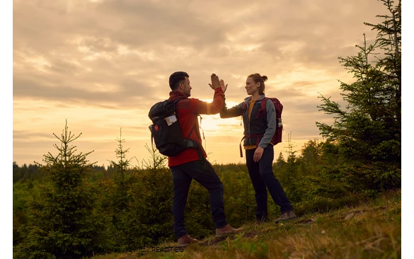Zwei Wandernde geben sich ein High Five im Sonnenuntergang