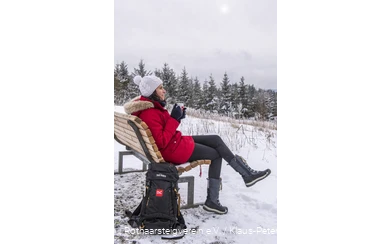 Frau blickt auf Rothaarsteig-Waldsofa in die Winterlandschaft