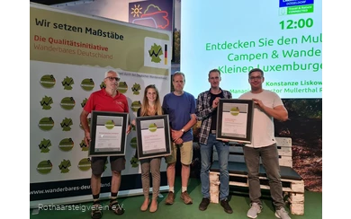 Gruppe auf einer Bühne mit Urkunden der zertifizierten Wege