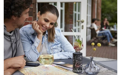 Ein Pärchen sitzt auf der Terrasse bei kalten Getränken und plant eine Wanderung