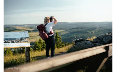 Frau steht auf dem Clemensberg am Rothaarsteig und fotografiert mit einer Kamera die Aussicht
