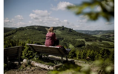 Wanderin sitz auf einer Bank und schaut in der Ferne auf die Bruchhauser Steine