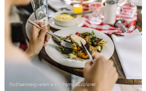 Nahaufnahme von einem Teller mit Antipasti und Händen die Besteck halten