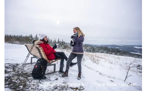 Zwei Frauen machen Pause an einer Rothaarsteig-Waldbank im Schnee