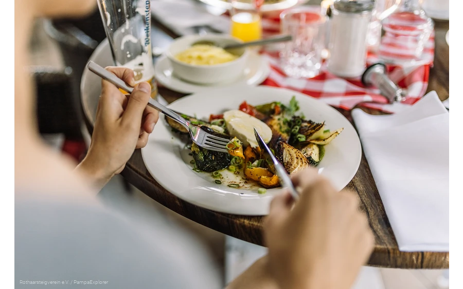 Nahaufnahme von einem Teller mit Antipasti und Händen die Besteck halten