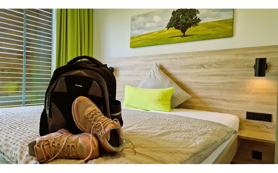 Zimmer im Hotel Fünf10 mit Wanderschuhen und Rucksack auf dem Bett
