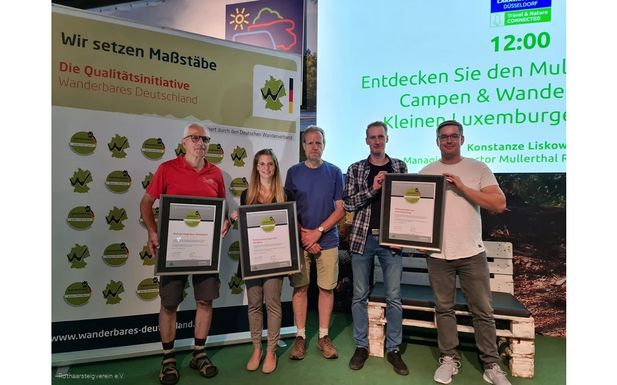 Gruppe auf einer Bühne mit Urkunden der zertifizierten Wege