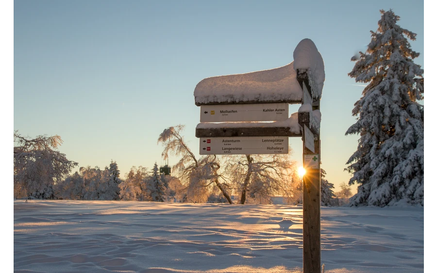 Verschneites Wanderschild am Rothaarsteig im Sonnenlicht