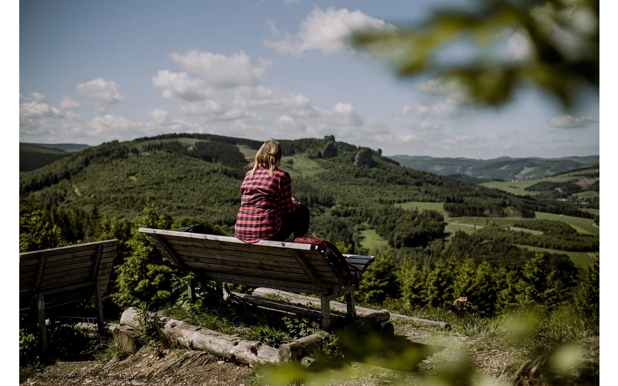 Wanderin sitz auf einer Bank und schaut in der Ferne auf die Bruchhauser Steine