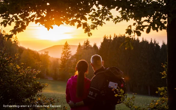 Zwei Rothaarsteig-Wanderer schauen in den Sonnenuntergang auf der Rothaarsteig-spur Sorper Panoramapfad