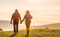 Zwei Rothaarsteig-Wanderer im Sonnenaufgang auf einer Wiese