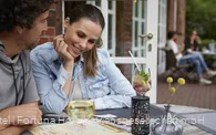 Ein Pärchen sitzt auf der Terrasse bei kalten Getränken und plant eine Wanderung