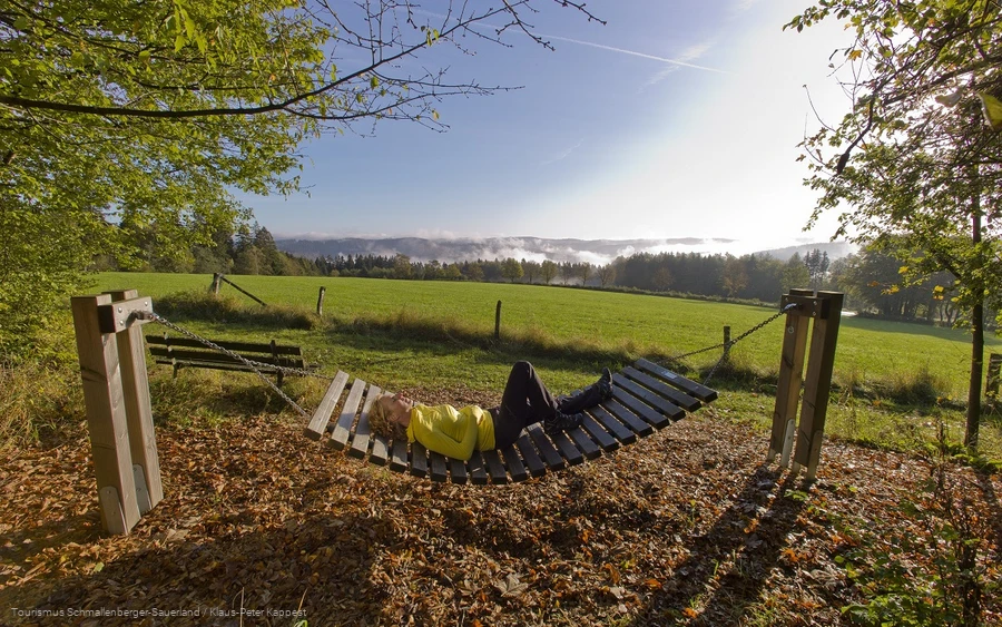 Hängematte Jagdhaus.jpg Frau liegt bei Sonnenschein in einer Rothaarsteig-Hängematte