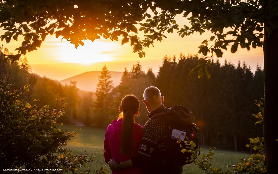 Zwei Rothaarsteig-Wanderer schauen in den Sonnenuntergang auf der Rothaarsteig-spur Sorper Panoramapfad