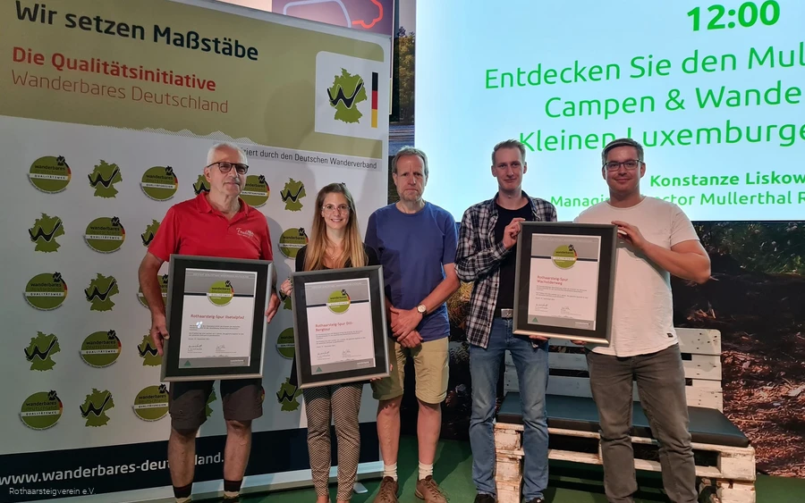 Gruppe auf einer Bühne mit Urkunden der zertifizierten Wege