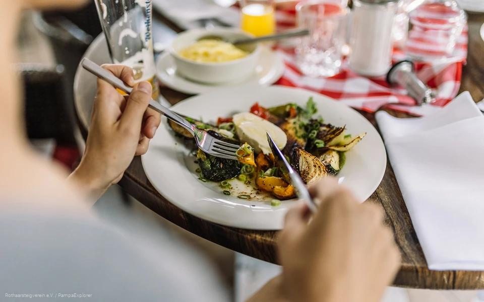 Nahaufnahme von einem Teller mit Antipasti und Händen die Besteck halten