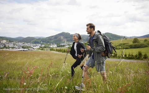 Ein wanderndes Pärchen auf einer Wiese nahe dem Sauerland Stern Hotel Willingen