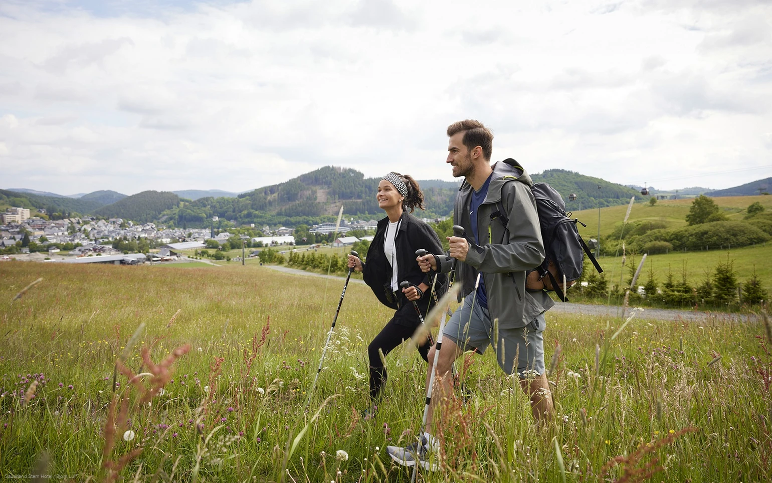 Ein wanderndes Pärchen auf einer Wiese nahe dem Sauerland Stern Hotel Willingen