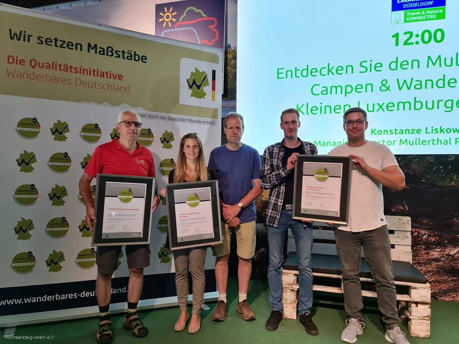 Gruppe auf einer Bühne mit Urkunden der zertifizierten Wege