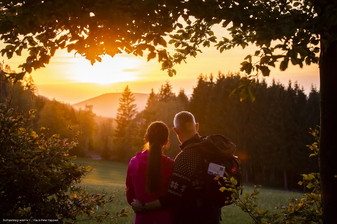 Zwei Rothaarsteig-Wanderer schauen in den Sonnenuntergang auf der Rothaarsteig-spur Sorper Panoramapfad