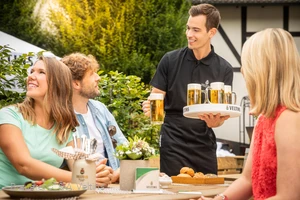 Eine Gruppe bekommt draußen am Tisch frisches Veltins serviert