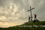Zwei Wandernde auf einem Berggipfel neben einem Gipfelkreuz