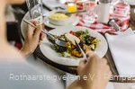 Nahaufnahme von einem Teller mit Antipasti und Händen die Besteck halten
