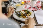 Nahaufnahme von einem Teller mit Antipasti und Händen die Besteck halten