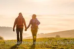 Zwei Rothaarsteig-Wanderer im Sonnenaufgang auf einer Wiese