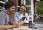 Ein Pärchen sitzt auf der Terrasse bei kalten Getränken und plant eine Wanderung