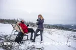 Zwei Frauen machen Pause an einer Rothaarsteig-Waldbank im Schnee