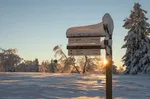 Verschneites Wanderschild am Rothaarsteig im Sonnenlicht