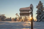 Verschneites Wanderschild am Rothaarsteig im Sonnenlicht